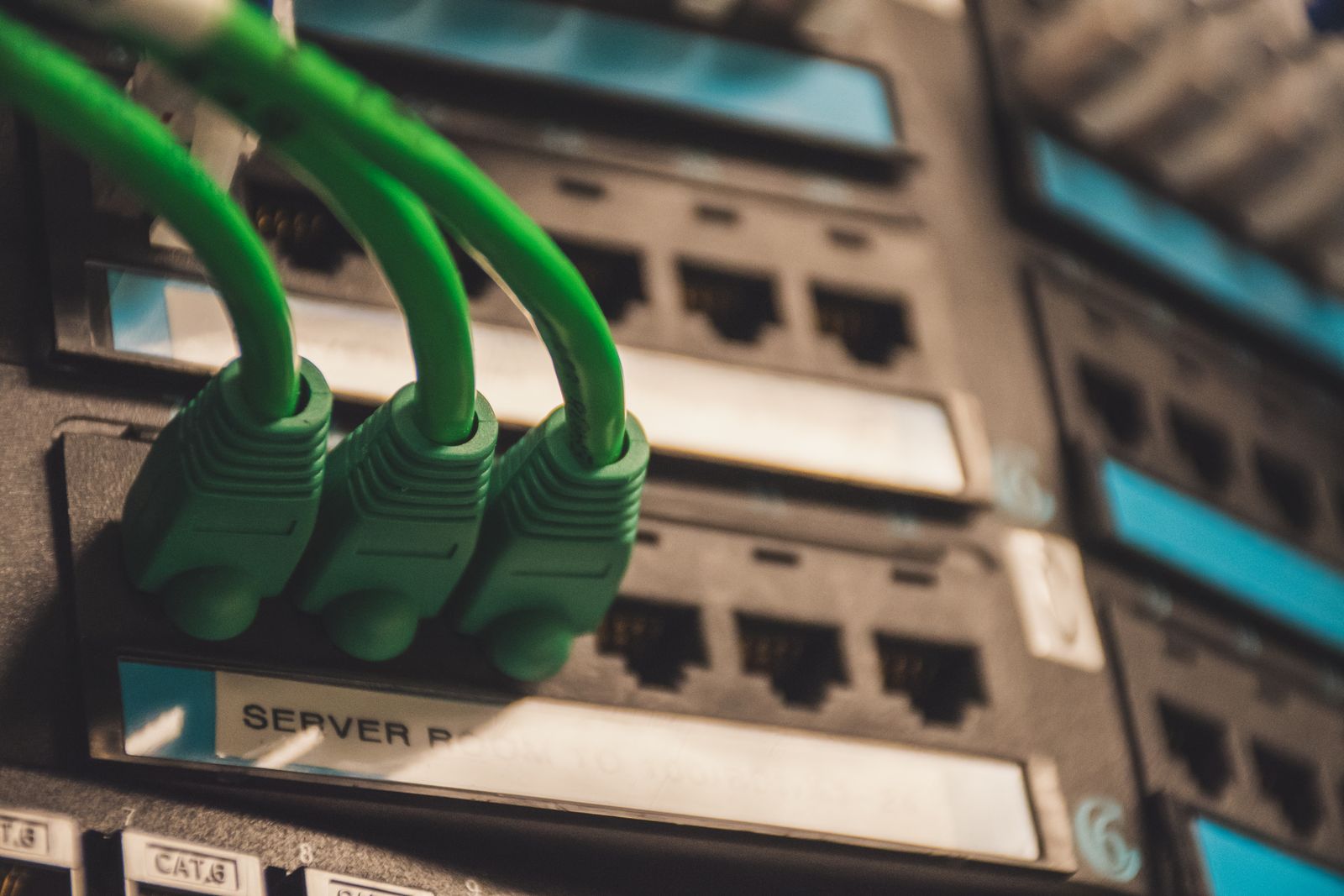 Green network cables connected to ports on a server rack